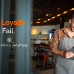 Restaurant manager reviewing loyalty program data on tablet highlighting why QSR customer retention strategies fail at scale
